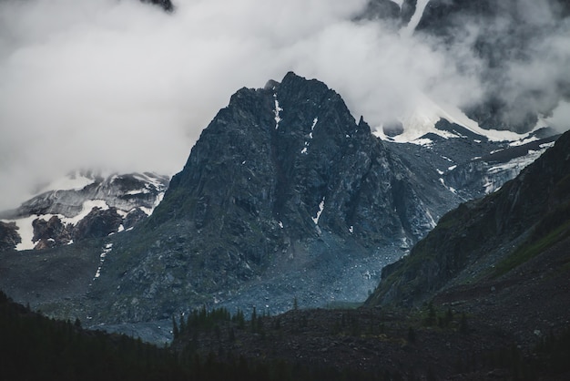 Premium Photo Bleak Dramatic Alpine Landscape With Big Cliff In Low Cloud Near Giant Snowy Mountain Wall In Dark Evening Dark Atmospheric Scenery With Snowy Rocks In Dense Fog Huge Glacier