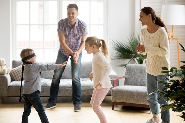 Blindfolded cute boy playing hide and seek game with family Free Photo