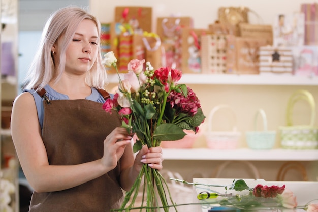 Premium Photo | Blond florist woman in apron in workspace of flower ...