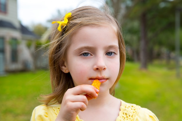 屋外の公園でコーンスナックを食べる金髪の子供女の子 プレミアム写真