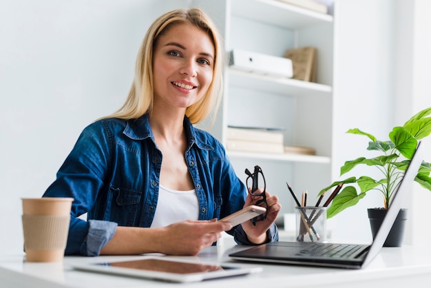 Free Photo | Blond working woman holding smartphone and glasses