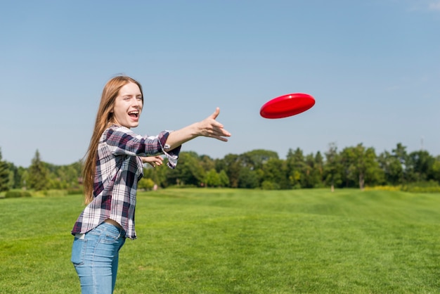 赤いフリスビーを投げるブロンドの女の子 無料の写真