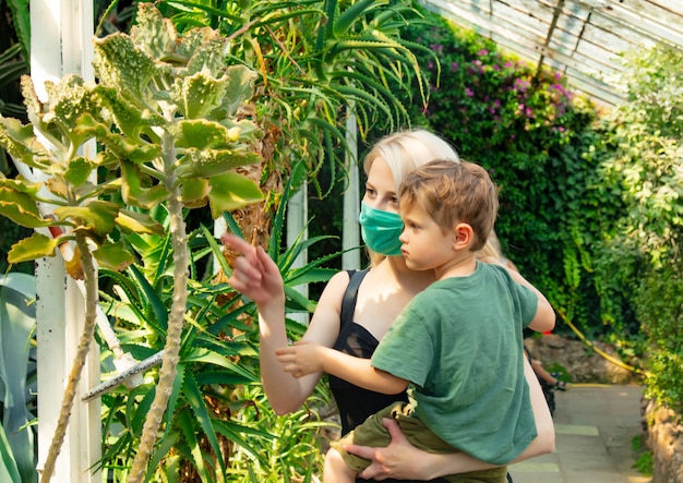 植物園のヤシの温室で子供とフェイスマスクで金髪の母 プレミアム写真