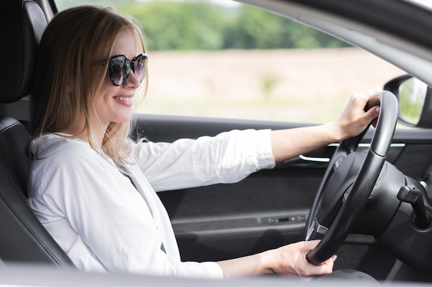 blonde woman driving car while wearing glasses 23 2148266184