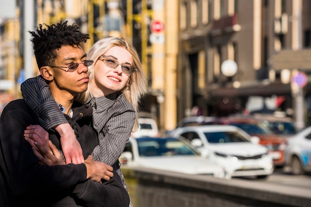 Blonde Young Woman Embracing Her Boyfriend On City Street Free Photo