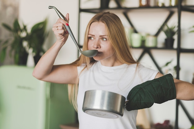 Blonde young woman tasting soup from the ladle Free Photo
