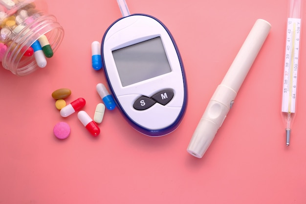 Premium Photo | Blood sugar measurement kits, pills and thermometer on pink