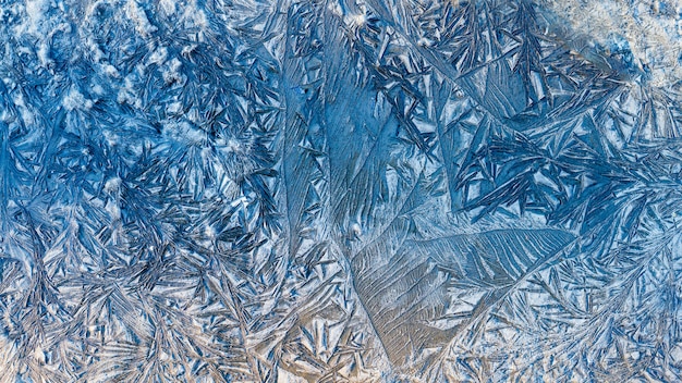 Blue beautiful winter frost patterns, abstract frost flowers texture on the road Premium Photo