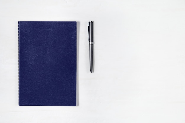 Premium Photo | Blue copybook and metallic pen on light background