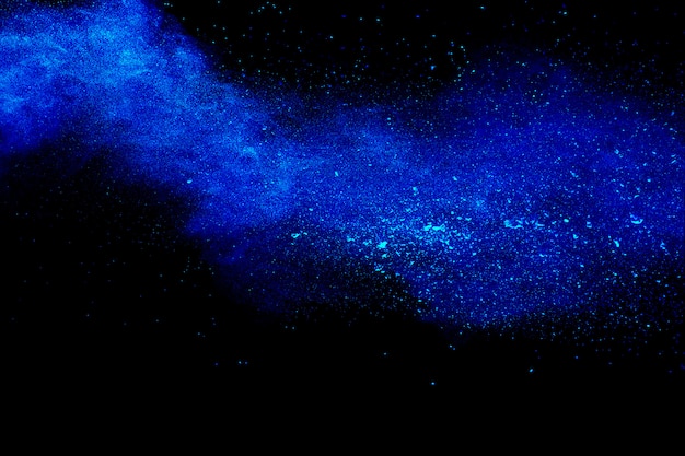 Premium Photo | Blue dust explosion on black background.