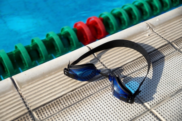 Premium Photo | Blue goggles for swimming on a side of the swimming pool