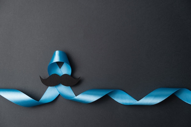 Blue ribbon with mustache on black background Premium Photo