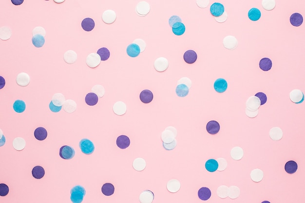 ピンク色の紙の背景にミニマルなスタイルのトップビューで青 白 ライラックの紙吹雪 プレミアム写真