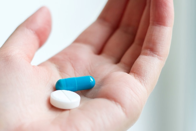 premium-photo-blue-and-white-pill-capsule-on-the-female-palm-on-white