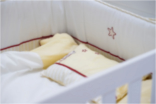 Blur Photo Of Yellow Baby Crib Pillow And Blanket Photo