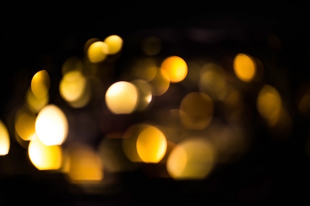Blurred gold bokeh on black background. glowing yellow lights bokeh in the dark, reflections Premium Photo