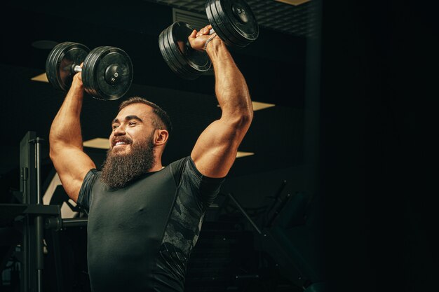 Premium Photo | Bodybuilder doing exercises with dumbbells in a dark gym