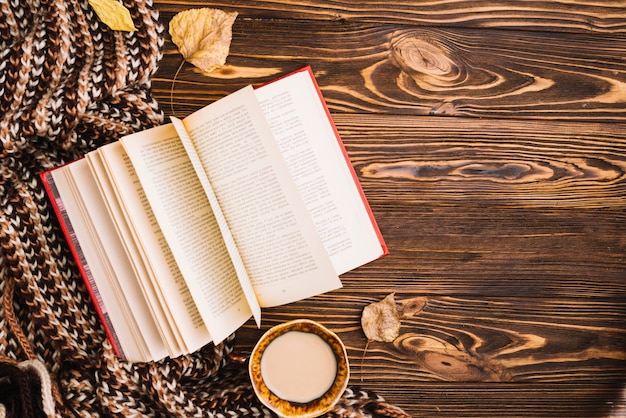 Book and drink near scarf and leaves Free Photo