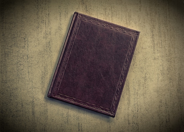 The book is dark purple on a grey grunge background, top view. tinted photo with vignetting, retro toned image Premium Photo