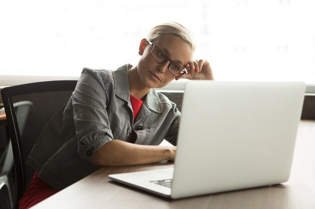 Free Photo | Bored businesswoman in glasses working at laptop