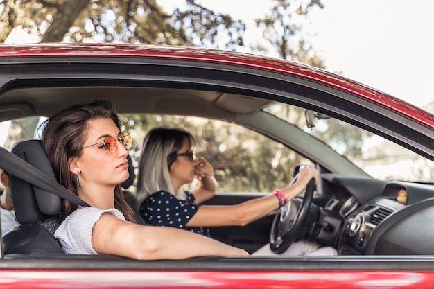 彼女の友人と近代的な車で旅行する退屈な若い女性 無料の写真