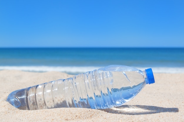 Premium Photo | A bottle of cool water on the beach near the sea.