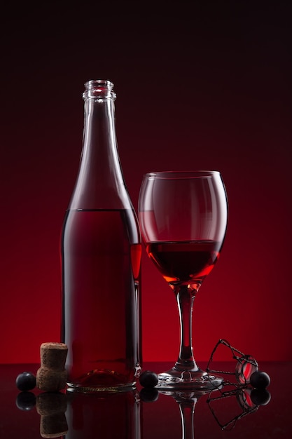 Premium Photo | Bottle and glass of lambrusco wine on red dark background.