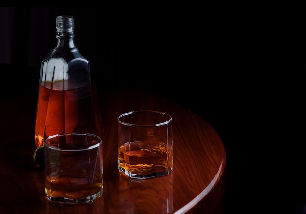 Premium Photo | A bottle and glasses of liquor on wooden table