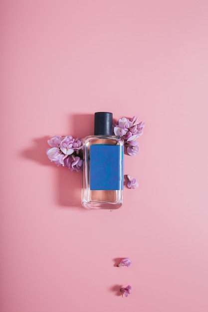 花とピンクの壁に香水のボトル 無料の写真