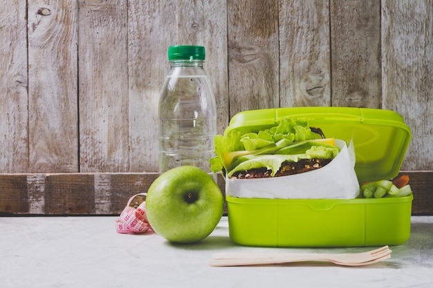 Bottle of water and apple next to a lunch box Free Photo