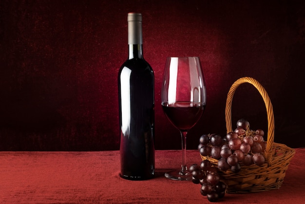 Bottle of red wine and glass with grapes basket Free Photo