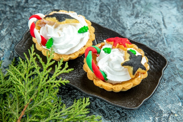 Bottom view small xmas tarts on black plate pine branch on grey table Free Photo