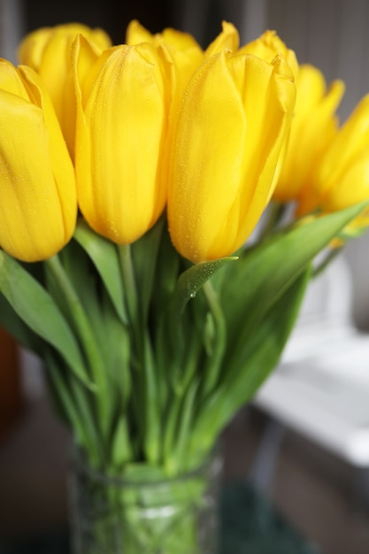 Premium Photo | A bouquet of fresh yellow tulips in a vase on a table ...