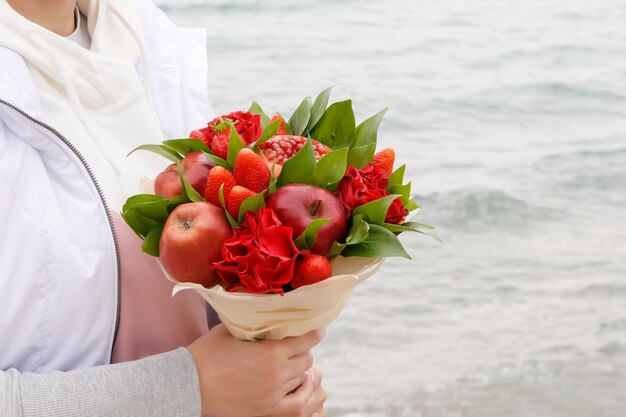 女性の手に花と果物の花束 プレミアム写真