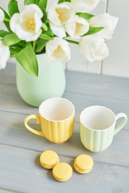 花瓶 レモンマカロン 2つのマグカップで新鮮な白いチューリップの花束 プレミアム写真