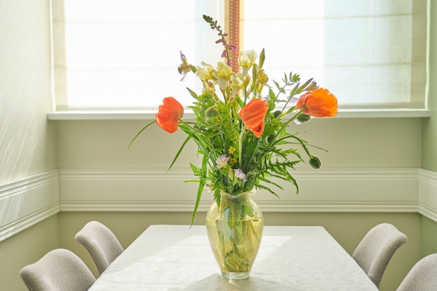 花瓶の春夏の花と赤いポピーの花束 リビングルームのテーブルの上に立って 窓の近くのダイニングエリア コピースペース プレミアム写真