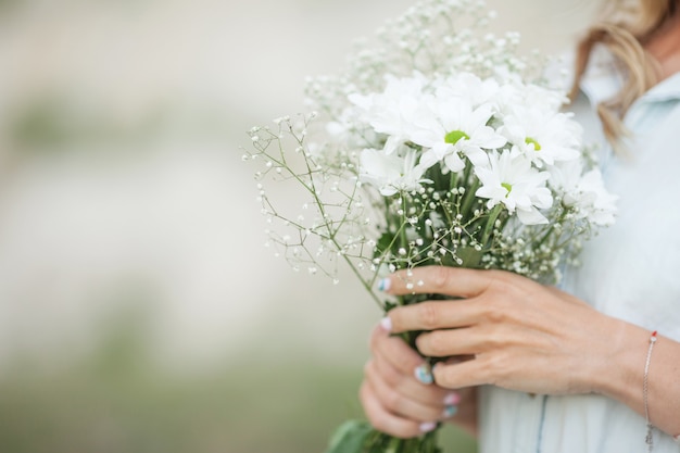 光の若い女性の手の中の白い花の花束 プレミアム写真