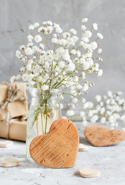 Premium Photo Bouquet Of Small White Flowers And Wooden Hearts On A Grey Background