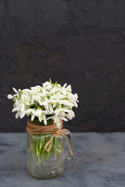 Bouquet of spring flowers of snowdrops in a glass vase.  Premium