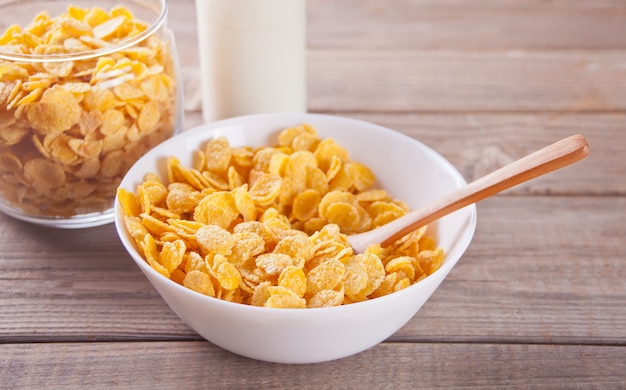 Premium Photo | A bowl of dry corn flakes cereal on wood