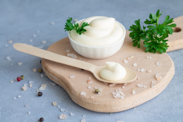 Bowl fresh organic homemade mayonnaise next to wooden spoon with mayo on wood board Premium Photo