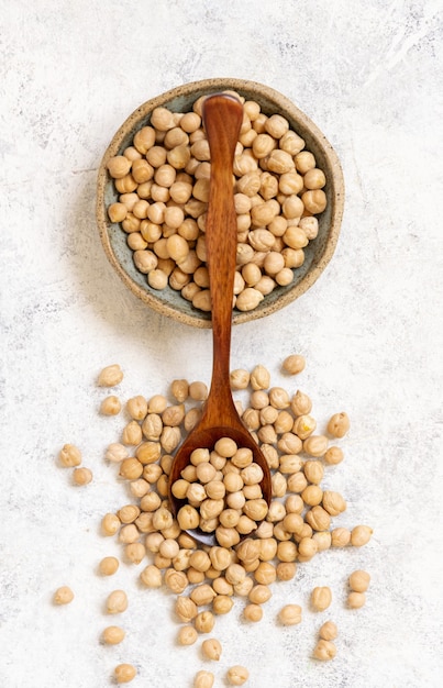 生の乾燥ひよこ豆のボウル キッチンタオルの上にスプーンの上面図 プレミアム写真