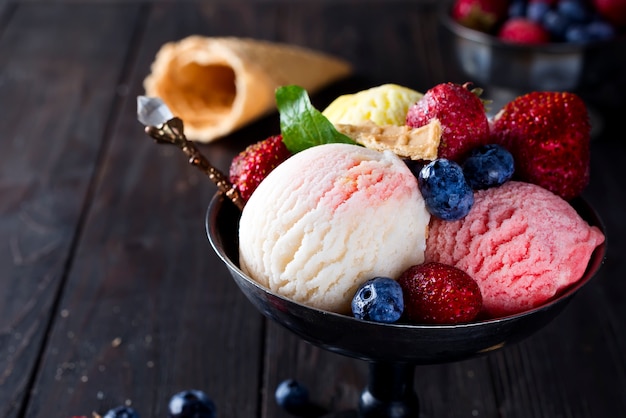 Bowl with ice cream with three different scoops of white, yellow, red colors and waffle cone Premium Photo