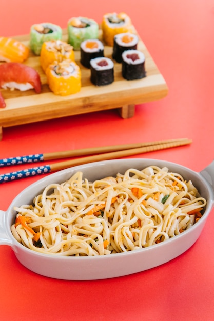 Free Photo | Bowl with noodles near chopsticks and sushi