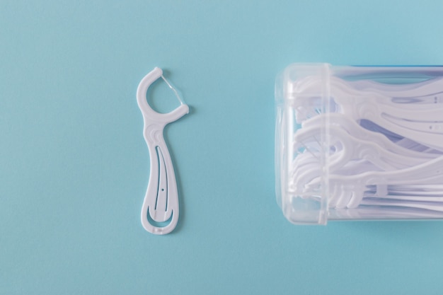 Premium Photo | A box of white dental flossers on bright blue background.