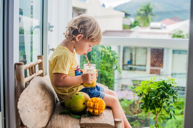 Premium Photo | Boy drinking juicy smoothie from mango in glass mason ...