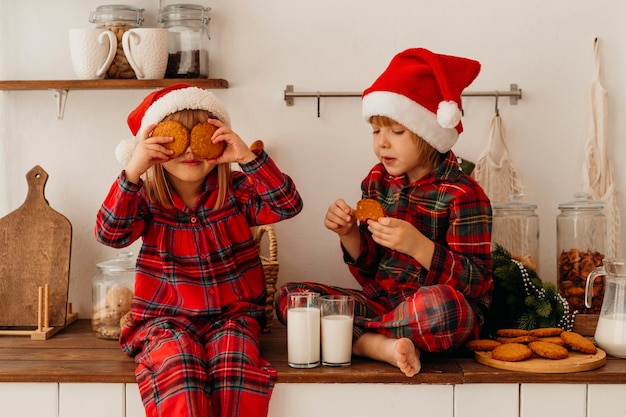 Boy and girl eating christmas cookies and drinking milk Free Photo