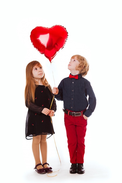 Boy and girl on a white background holding a balloon red heart Premium Photo
