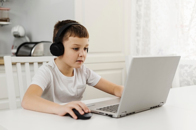 Boy a home playing on laptop and wearing headphones Free Photo