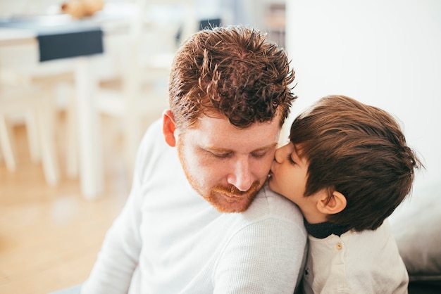 Boy kissing dad on cheek Photo | Free Download